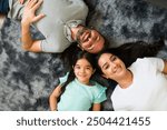 Happy family is lying down on a furry rug in their living room, enjoying their time together