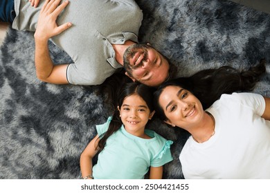 Happy family is lying down on a furry rug in their living room, enjoying their time together - Powered by Shutterstock