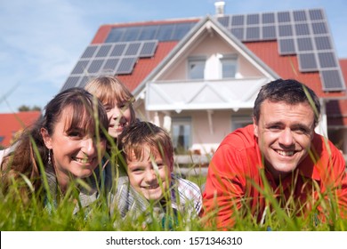 Happy family lying in grass in front of house with solar panels