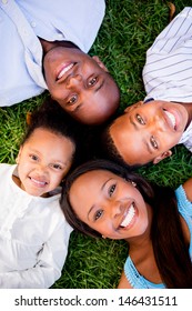 Happy Family Lying On The Grass With Their Heads Together 