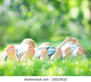 Happy Family Lying On Green Grass In Spring Park. Healthy Lifestyle Concept. Farmland Vacations