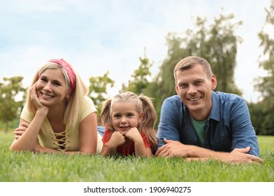 Happy Family Lying On Green Grass In Park