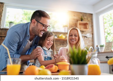 Happy Family Makes Orange Juice For Breakfast In Their Kitchen.Family,healthy,fun And Lifestyle Concept.