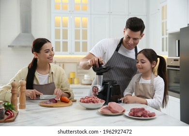 Happy Family Making Dinner Together In Kitchen, Father And Daughter Using Modern Meat Grinder While Mother Cutting Onion