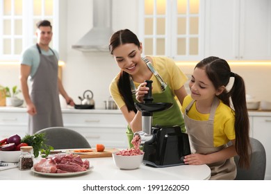 Happy family making dinner together in kitchen, mother and daughter using modern meat grinder