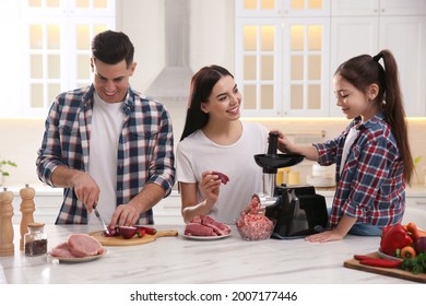 Happy Family Making Dinner Together In Kitchen, Mother And Daughter Using Modern Meat Grinder While Father Cutting Onion