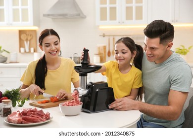 Happy Family Making Dinner Together In Kitchen, Father And Daughter Using Modern Meat Grinder While Mother Cutting Carrot