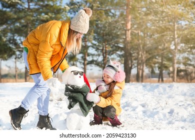 Happy Family Making Snowman In Park