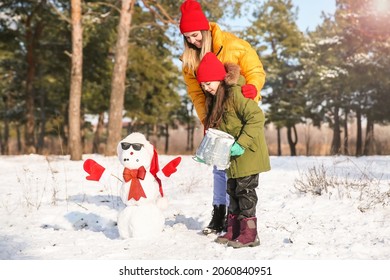 Happy Family Making Snowman In Park