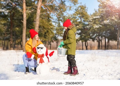 Happy Family Making Snowman In Park