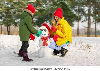 Happy Family Making Snowman In Park