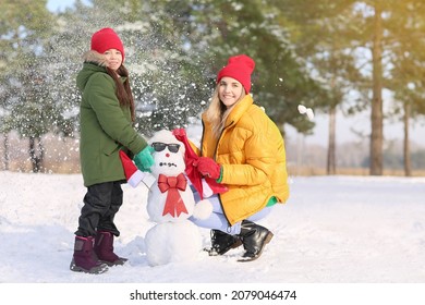 Happy Family Making Snowman In Park