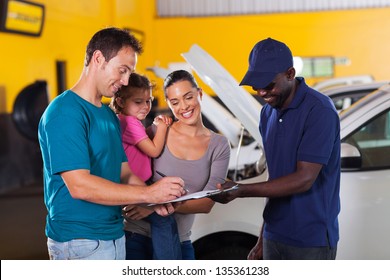 Happy Family Man Signing Invoice In Car Repair Shop