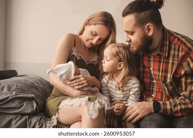 Happy family meets new baby. Mom, dad, older daughter and newborn son. Parents introduce older sister to baby	