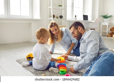 Happy Family. Mom, Dad And Baby Playing At Home With A Colored Pyramid Sitting On The Floor In The Living Room. Parents Together Develop Their Child. Concept Of Family And Child Development.