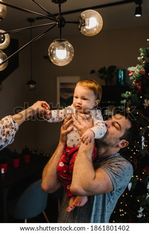 Happy family: mom, dad hugging little son near the Christmas tree. Enjoying love hugs, holidays people. Togetherness concept. Merry Christmas and Happy New year.