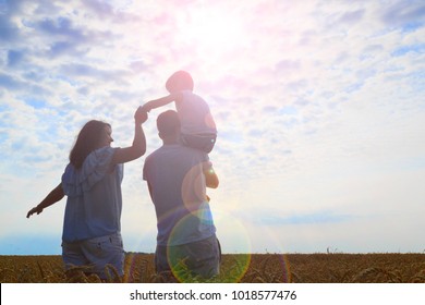 Happy Family. Mom Dad And Son Look At The Sun In The Wheat Field. Back View.