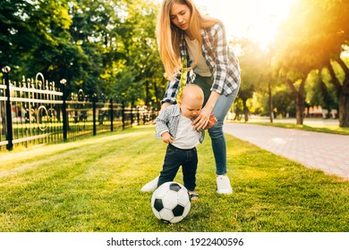 Happy Family, Mom And Her Little Son Are Playing Soccer Ball In The Park. Family Leisure