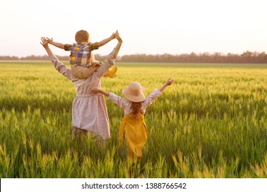 Happy Family, Mom, Son And Girl In Straw Hat In Wheat Field At Sunset.  The Concept Of Organic Farming And Healthy Lifestyle, Healthy Food, Happiness And Joy