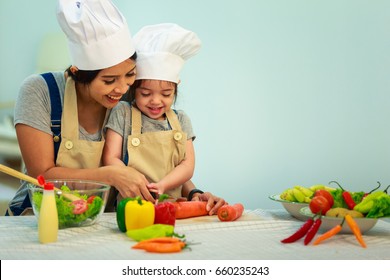 Happy Family Mom Teaching Cute Girl Preparing And Cooking Healthy Salad For The First Time. First Lesson And Healthy Lifestyle Concept.