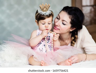 happy family. Mother and baby daughter plays, hugging. Playing mom's jewelry