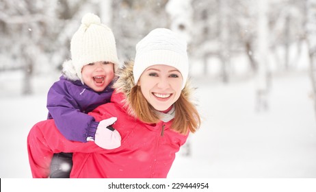 Happy Family Mother And Baby Girl Daughter Playing And Laughing In Winter Outdoors In The Snow