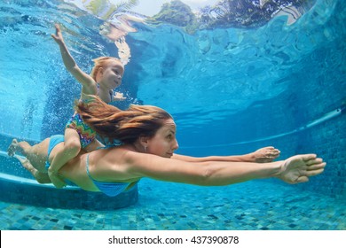 Happy Family - Mother, Baby Girl Learn To Swim And Dive Underwater With Fun In Swimming Pool. Healthy Lifestyle, Active Parents, People Water Sports Activities On Summer Holidays With Child.