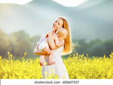 Happy Family Mother And Baby Hugging In A Meadow  Yellow Flowers On Nature In Summer
