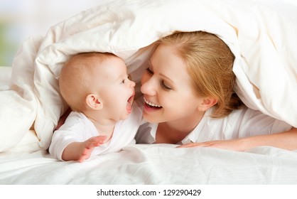 happy family. Mother and baby playing and smiling under a blanket