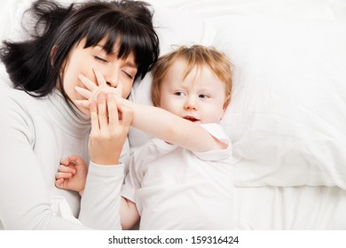 happy family. Mother and baby playing and smiling in bed - Shutterstock ID 159316424