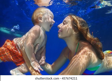 Happy Family - Mother, Baby Son Learn To Swim And Dive Underwater With Fun In Pool. Healthy Lifestyle, Active Parent, People Water Sports Activity And Swimming Lessons On Summer Holiday With Child