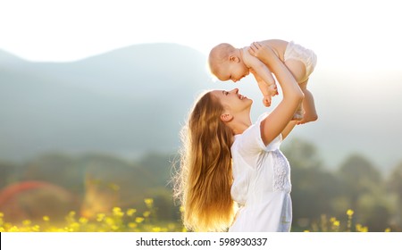 Happy Family Mother And Baby Son In A Meadow  Yellow Flowers On Nature In Summer
