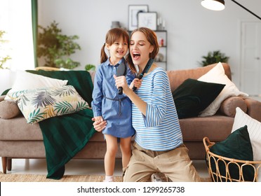 happy family mother and child daughter play at home and sing with combs