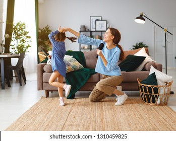 Happy Family Mother And Child Daughter Play At Home And Sing With Combs
