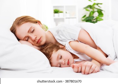 Happy Family Mother And Child Daughter Sleeping In Bed Embracing