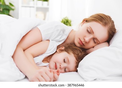 Happy Family Mother And Child Daughter Sleeping In Bed Embracing