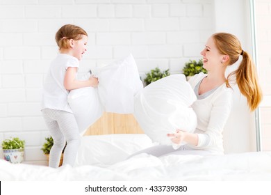 Happy Family Mother And Child Daughter Playing On Bed And Pillow Fight