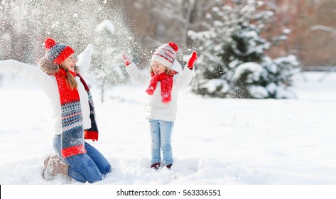 Happy Family Mother And Child Daughter Playing And  Throws Up Snow On Winter Walk
