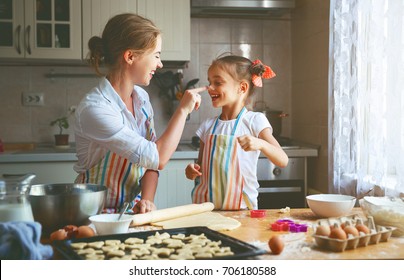 Happy family mother and child daughter bake kneading dough in the kitchen