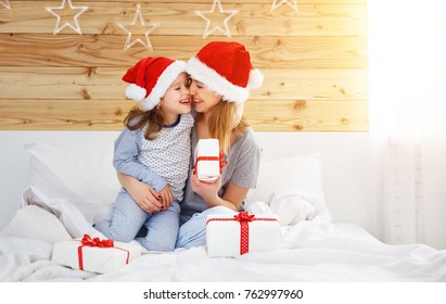 Happy Family Mother And Child Daughter Hugging And Giving Gifts In Bed On Christmas Morning
