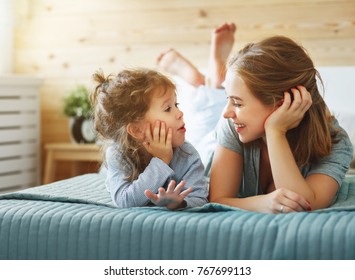 Happy family mother and child daughter play and laughing in bed