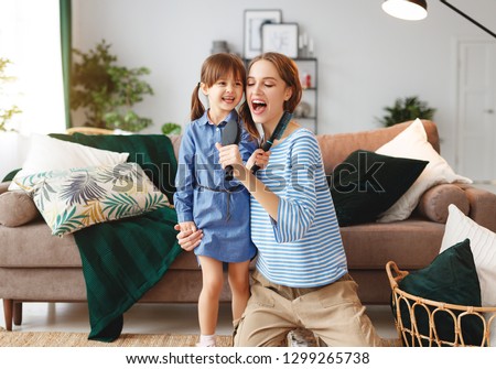 happy family mother and child daughter play at home and sing with combs
