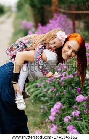 Happy family, mother and child daughter embrace in flowers. Summ