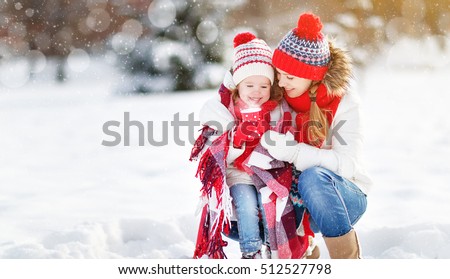 happy family mother and child daughter on a winter walk outdoors drinking tea