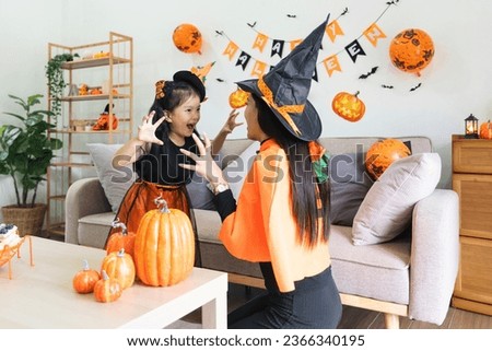 Happy family mother and child happy girl with Halloween at home together beautifully decorated. Mother teasingly playing with daughter