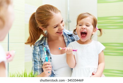 happy family mother and child little girl cleans teeth with a toothbrush in the bathroom