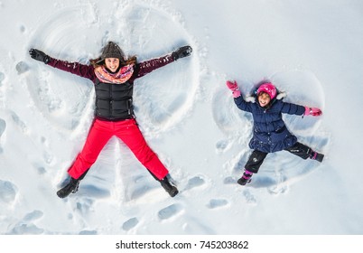 Happy family, mother and cute daughter making snow angel while lying on snow.  - Powered by Shutterstock