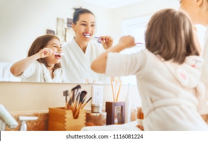 Happy family! Mother and daughter child girl are brushing teeth toothbrushes in the bathroom.