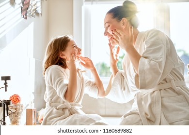 Happy Family! Mother And Daughter Child Girl Are Caring For Skin In The Bathroom.