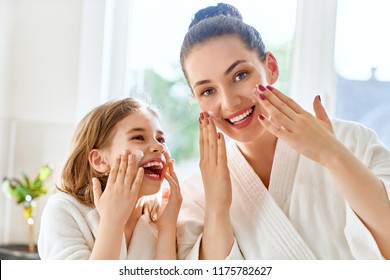 Happy family! Mother and daughter child girl are caring for skin in the bathroom.